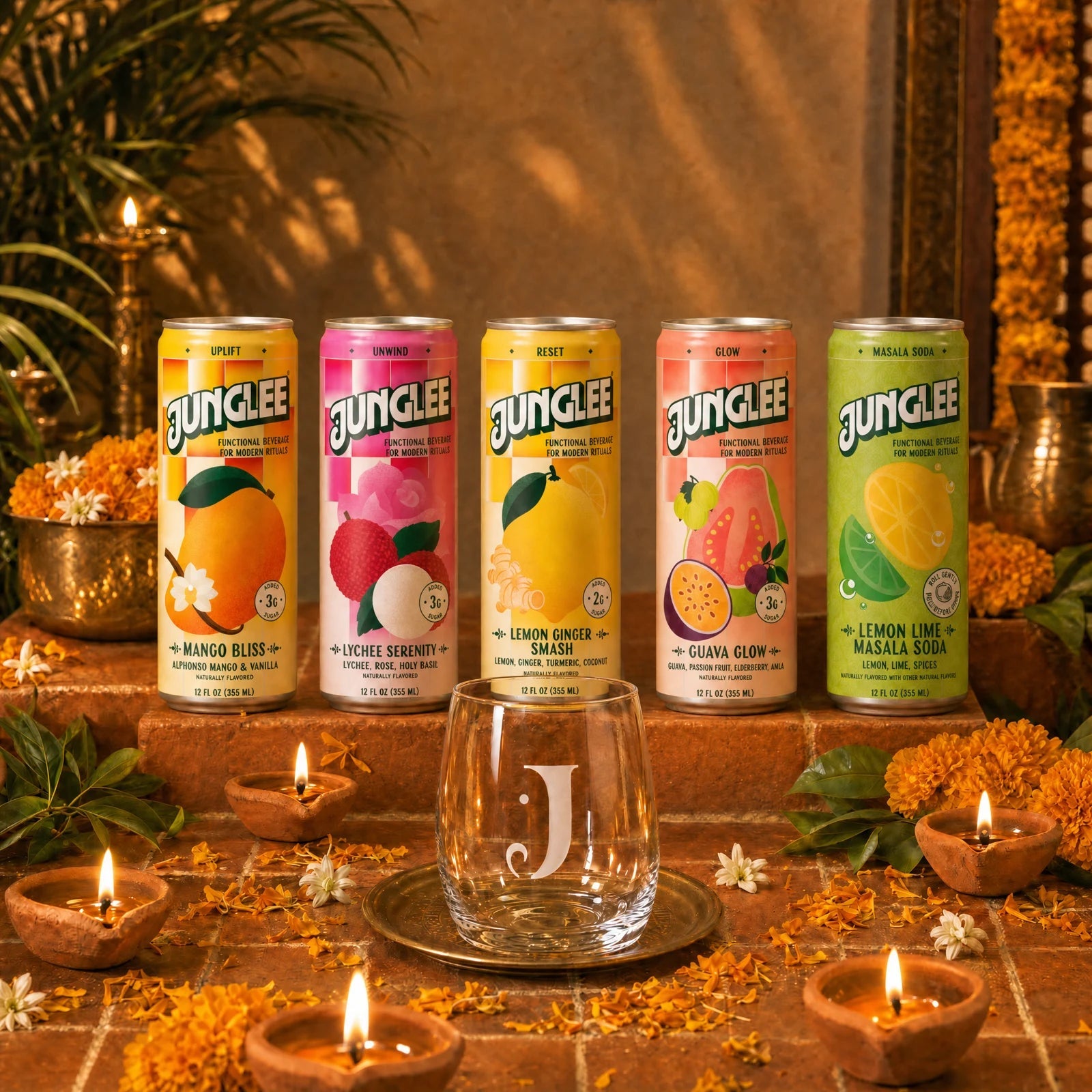 All five Junglee 12 oz cans and the engraved Junglee J glass on terracotta tiles with marigolds and glowing Diwali diyas
