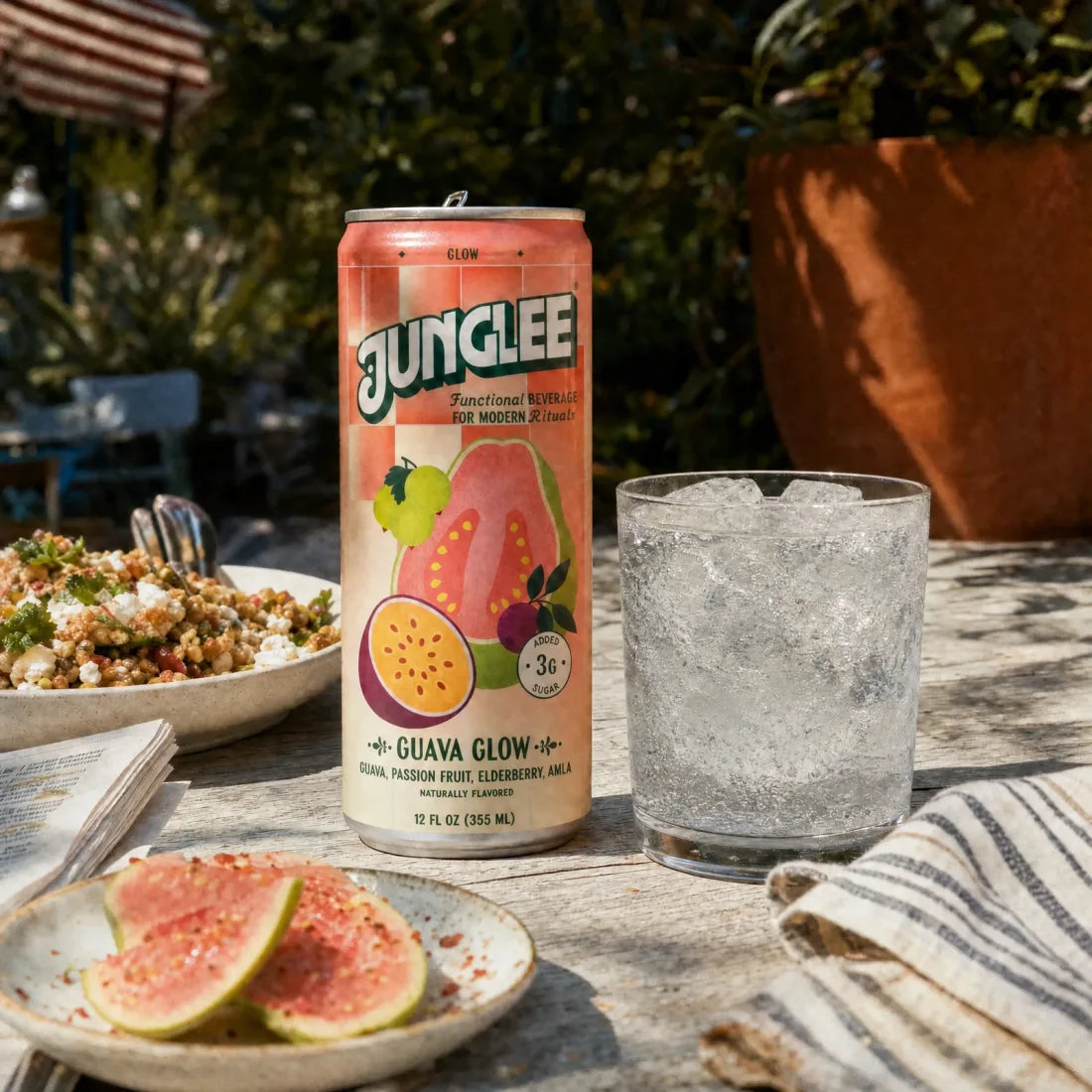 Guava Glow and a clear sparkling drink beside lunch on a sunlit patio