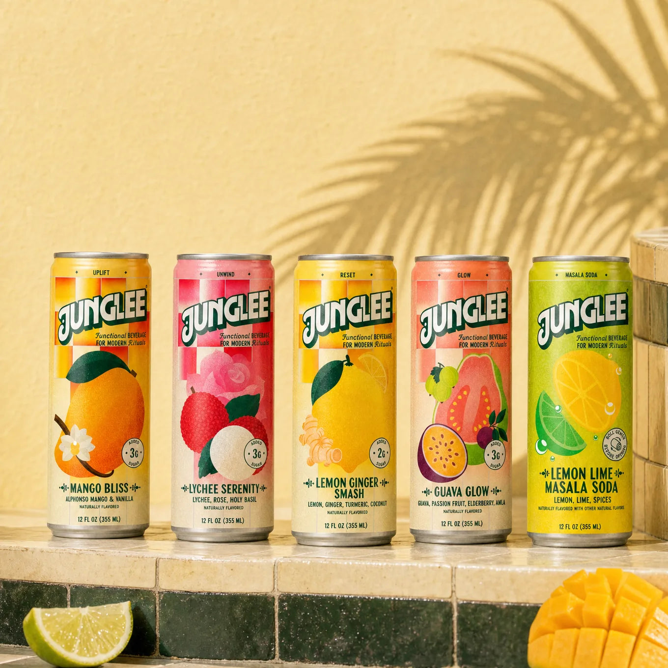All five Junglee flavors lined up on ivory and deep green tiles against a sunlit wall, with fresh mango and lime