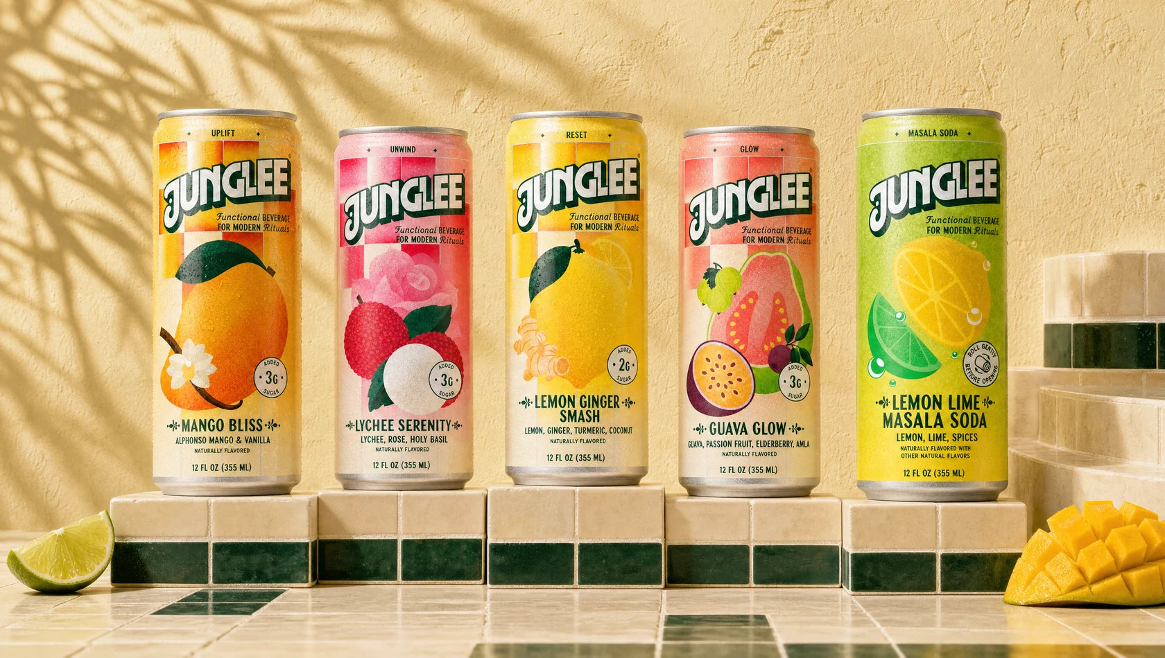 All five Junglee flavors lined up on ivory and deep green tiles against a sunlit wall: Mango Bliss, Lychee Serenity, Lemon Ginger Smash, Guava Glow and Lemon Lime Masala Soda.